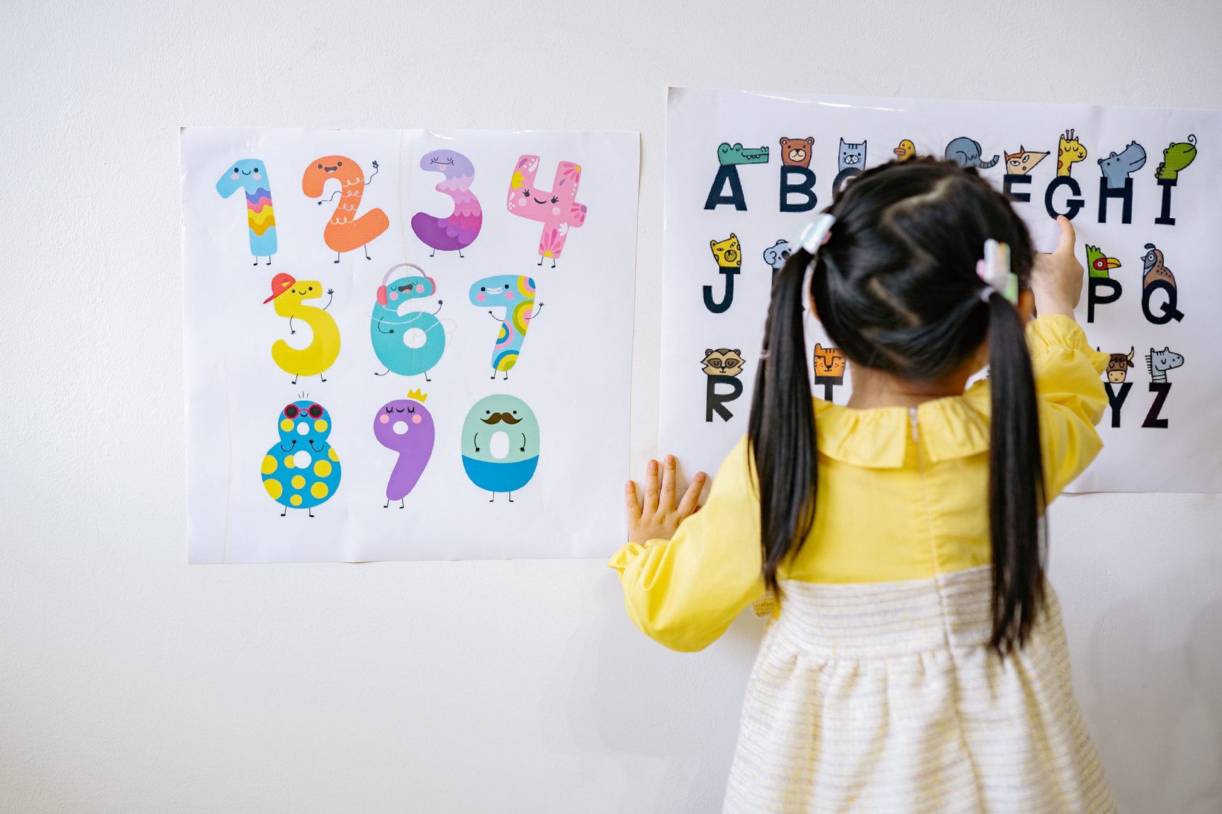 Woman in Yellow Long Sleeve Shirt Standing in Front of White Wall With Assorted Stickers