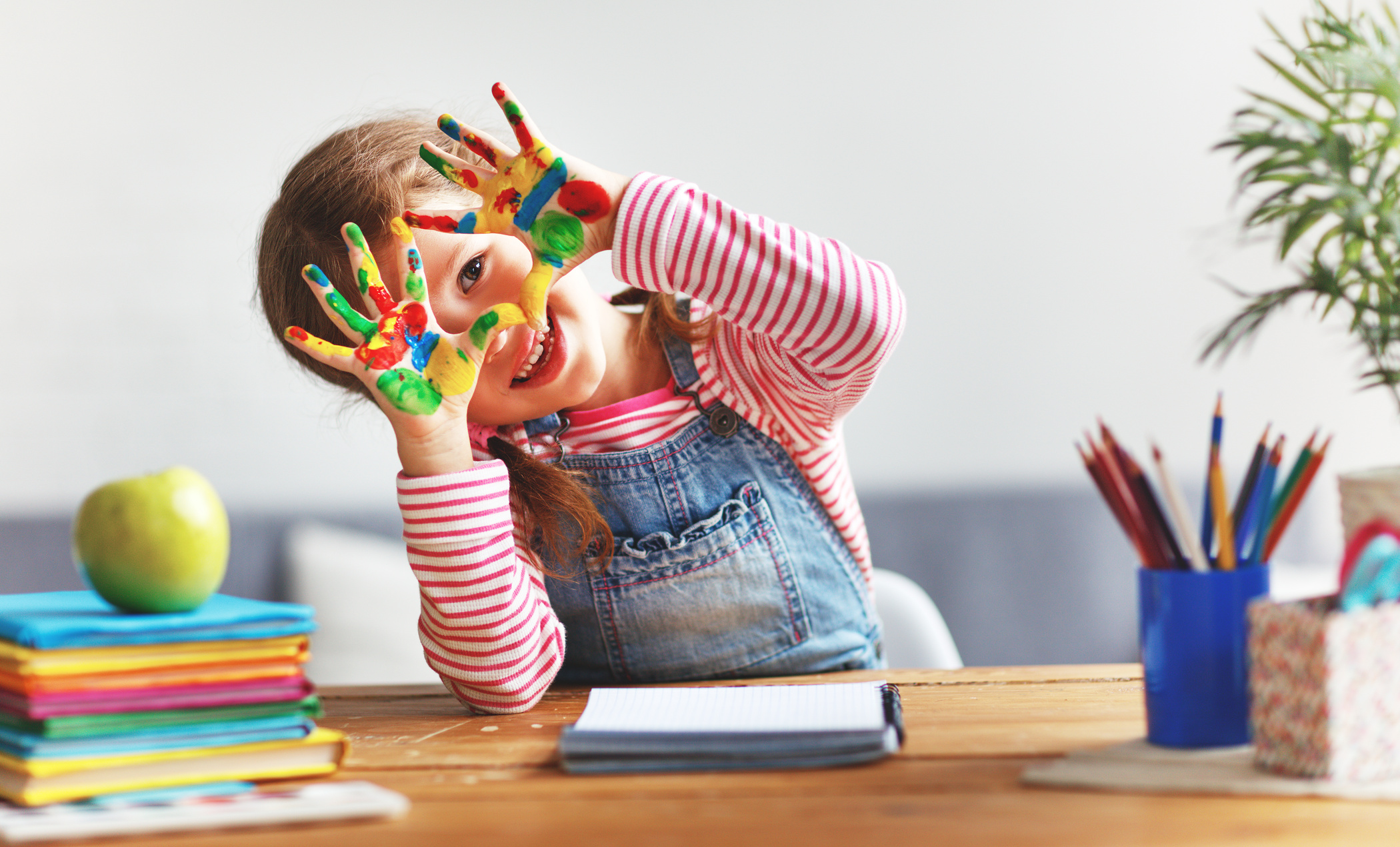 funny child girl draws laughing shows hands dirty with paint